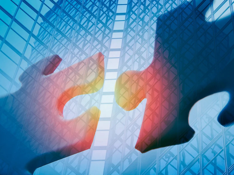 Two puzzle pieces coming together with office towers in the background.