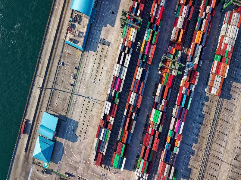 An aerial shot of a row of colourful shipping containers at a facility next to the water.