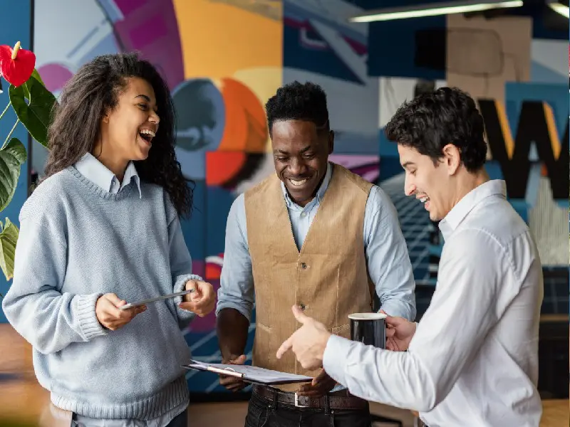 3 young co-workers happily engaging over a clipboard.