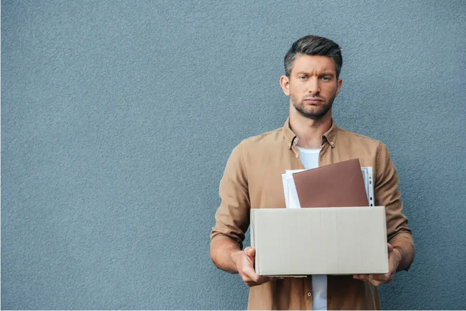A young man holds a box of his possessions.