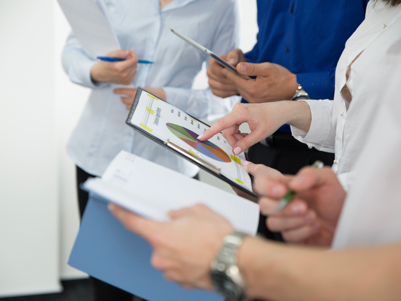 Close-up of business professionals reviewing charts and data on a tablet during a meeting.