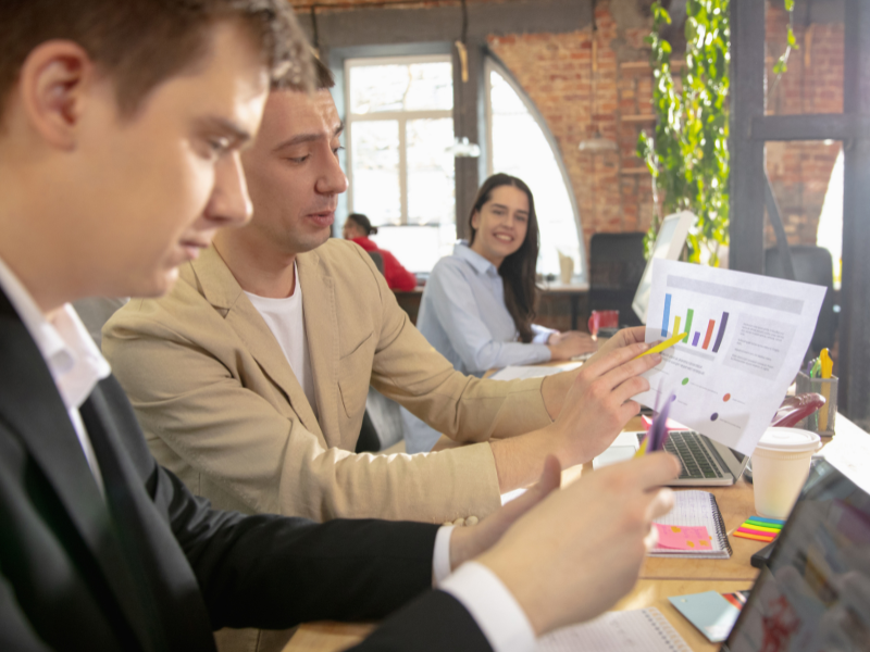 Business professionals discussing a growth chart during a strategy meeting in a modern office space.