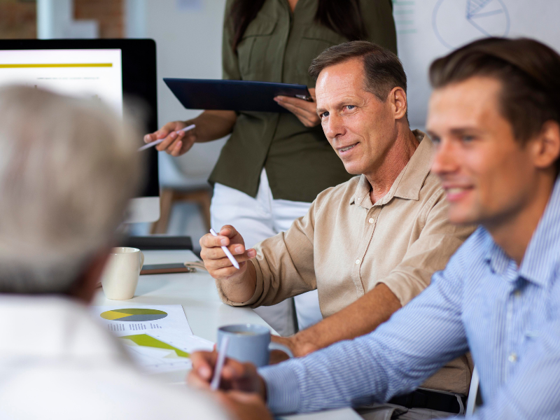 A group of professionals engaged in a leadership development training session, discussing business strategies with charts and reports on the table.