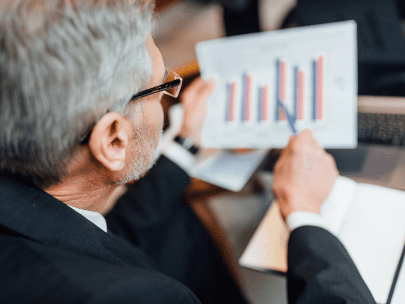 Business consultant analyzing a bar graph with sales trends during a strategic planning session.