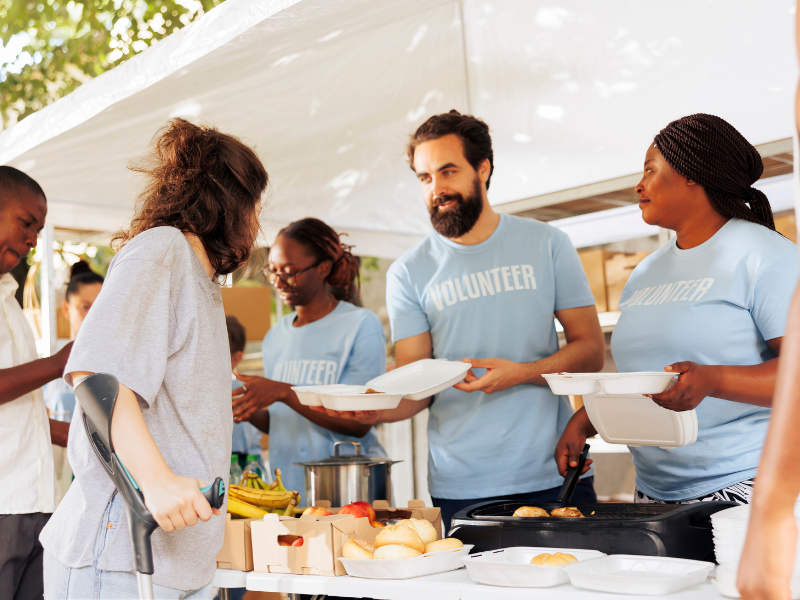 giving back the business benefits of community engagement Volunteers serving food at a community outreach event