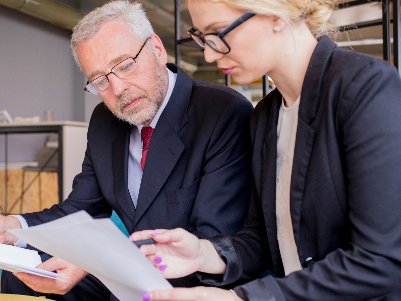 Business buyer and seller reviewing print business documents together during a meeting.