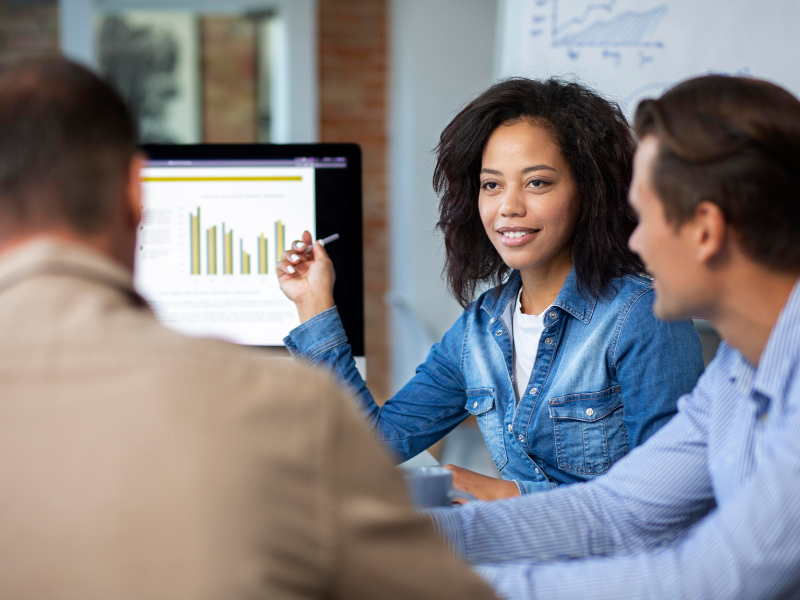 Business professional analyzing performance data on a laptop in a warehouse, representing operational benchmarking and performance tracking.