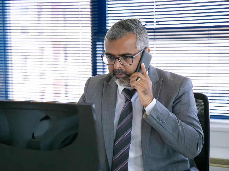 Business professional on the phone reviewing data on a computer, representing focused sales strategy and competitive account targeting.