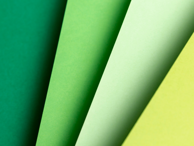 Close-up of layered green paper sheets, symbolizing sustainable packaging materials and environmentally responsible print production.