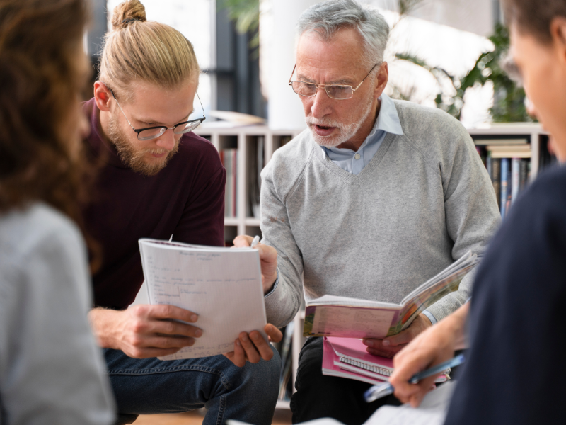 ai workforce development for print automation roi Senior employee reviewing documents with a younger colleague, representing knowledge transfer and workforce upskilling in print operations.
