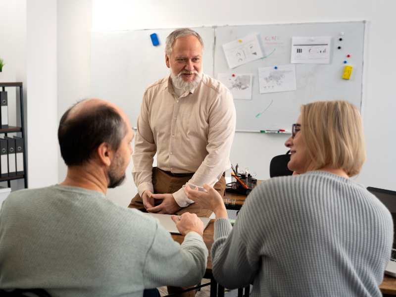 Manager leading a discussion with two employees in a meeting, representing mentorship, coaching, and team development.