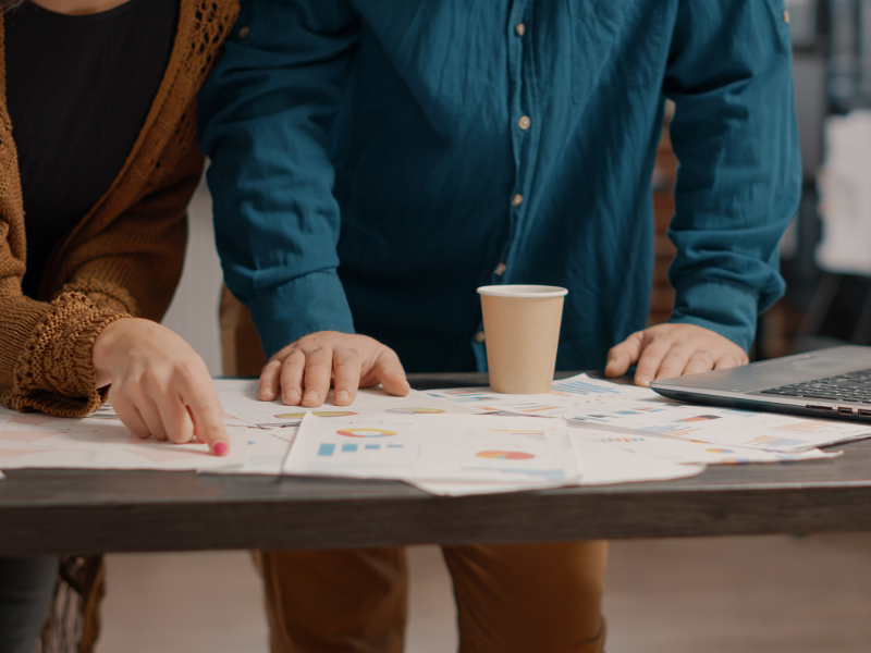 Business team reviewing reports and discussing plans at a table, representing structured planning and collaboration during a post-sale transition.