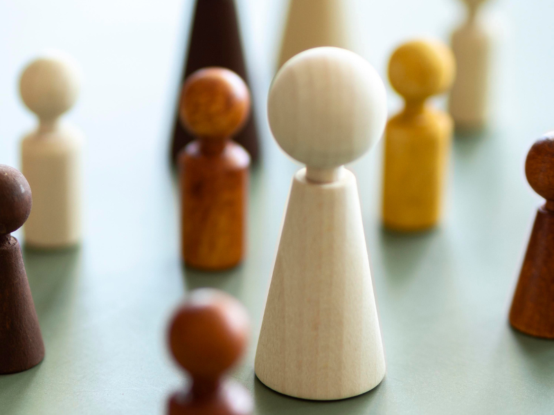 Wooden game-piece figures arranged on a table, symbolizing workforce planning, staffing flexibility, and strategic talent decisions.