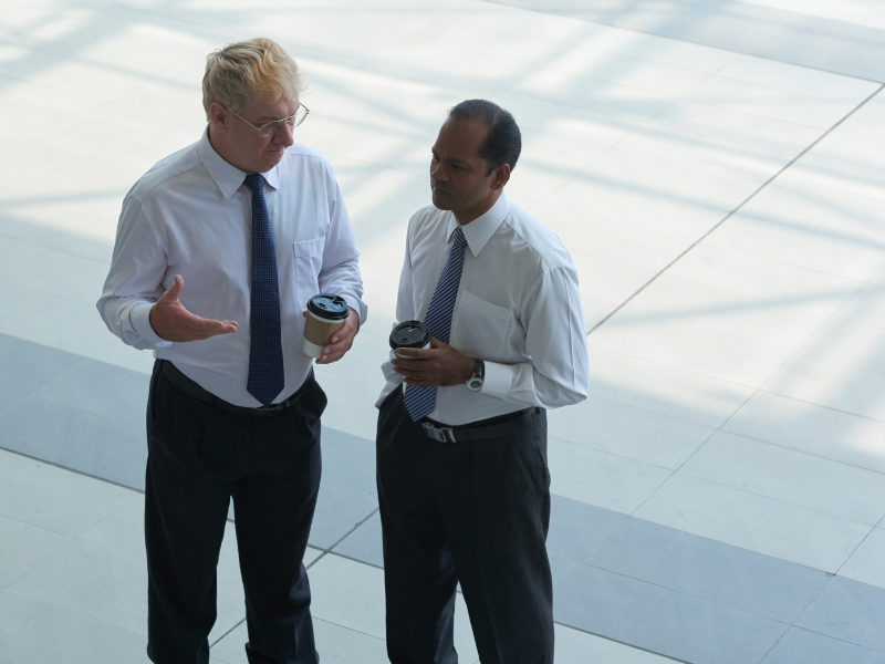 Two business leaders talking with coffee during an acquisition integration discussion