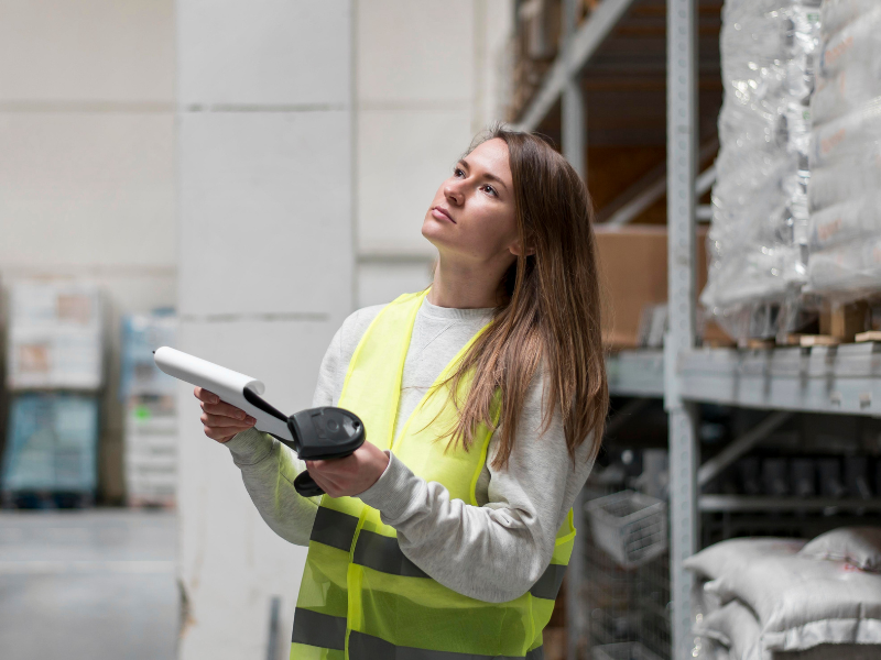 ethical supply chains in print and packaging Warehouse manager reviews materials inventory with scanner, supporting ethical supply chain oversight in packaging.