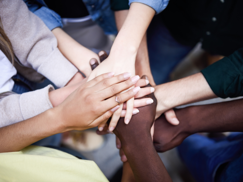 inclusive workplaces in the print industry Diverse team members place hands together, representing inclusive workplaces and stronger retention in print industry