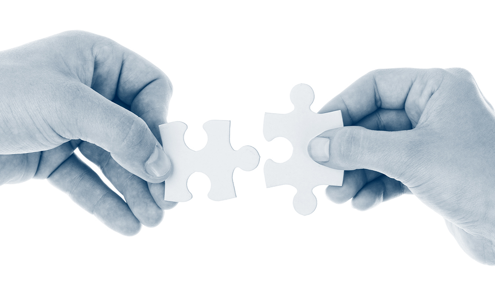 Two hands holding puzzle pieces symbolizing teamwork