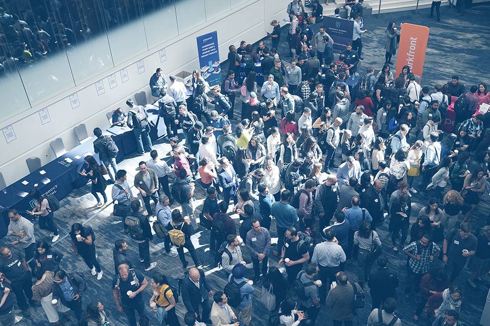 An aerial shot of a crowd of professionals at a trade show in a large convention centre