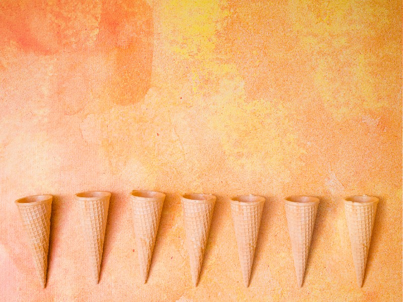 7 ice cream cones against an orange background.