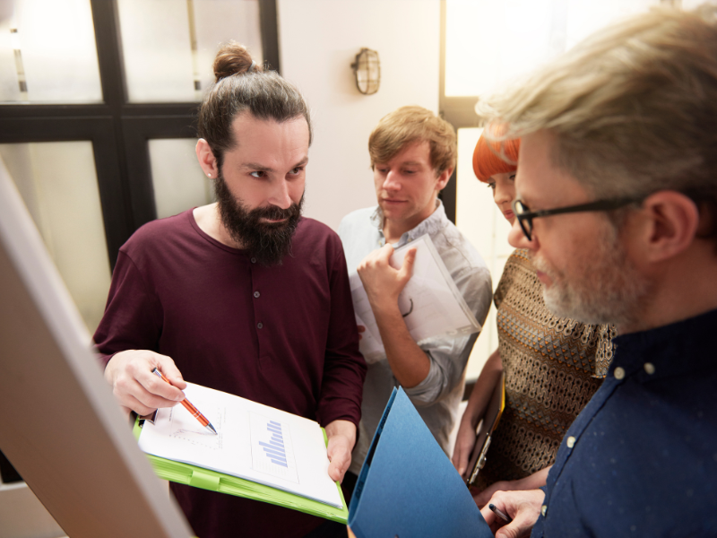 A team of professionals reviewing graphs and data during a meeting, discussing business strategies and change management.