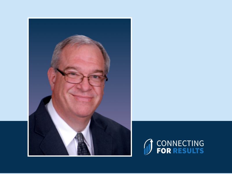 A professional headshot of Martin Nuiver, Revenue and Organization Improvement Specialist at Connecting for Results, wearing a dark suit, white shirt, and patterned tie, smiling against a blue gradient background.